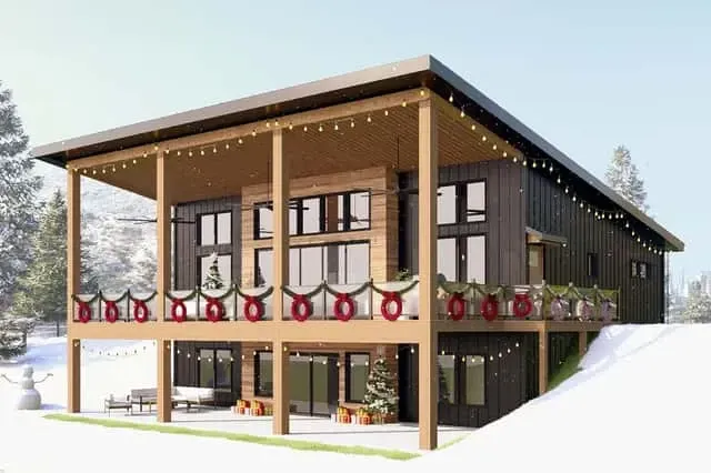Plan 135233GRA holiday season exterior with warm wreath and lit windows showing year-round livability and curb appeal in winter mountain setting
