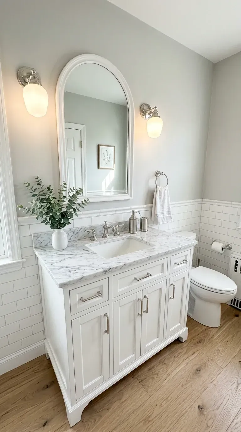 Charleston classic bathroom with white subway tile wainscoting dark grout light gray upper walls white vanity Carrara marble countertop arched white mirror polished chrome fixtures and light wood floors