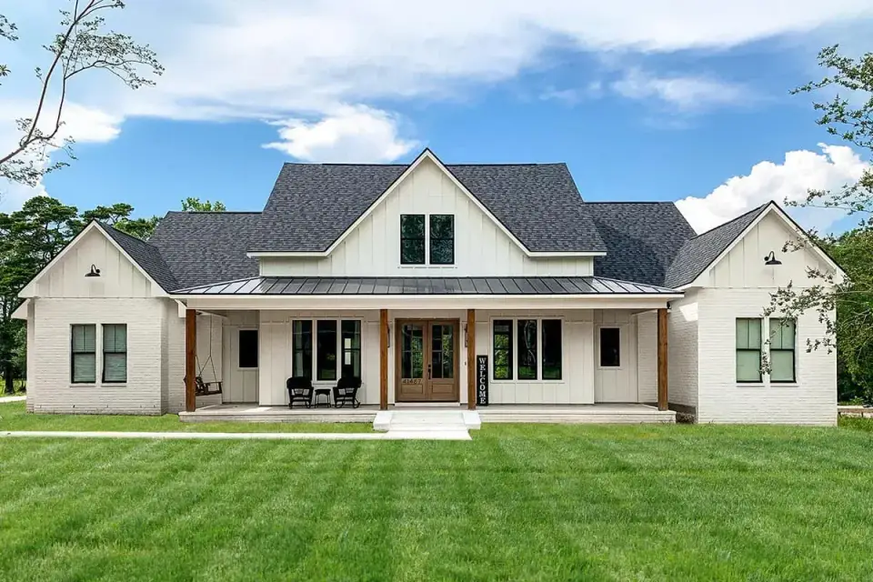 Plan 56478SM rendered landscape view with mature trees and front lawn showing how the symmetrical farmhouse facade composes on a typical 90-foot lot