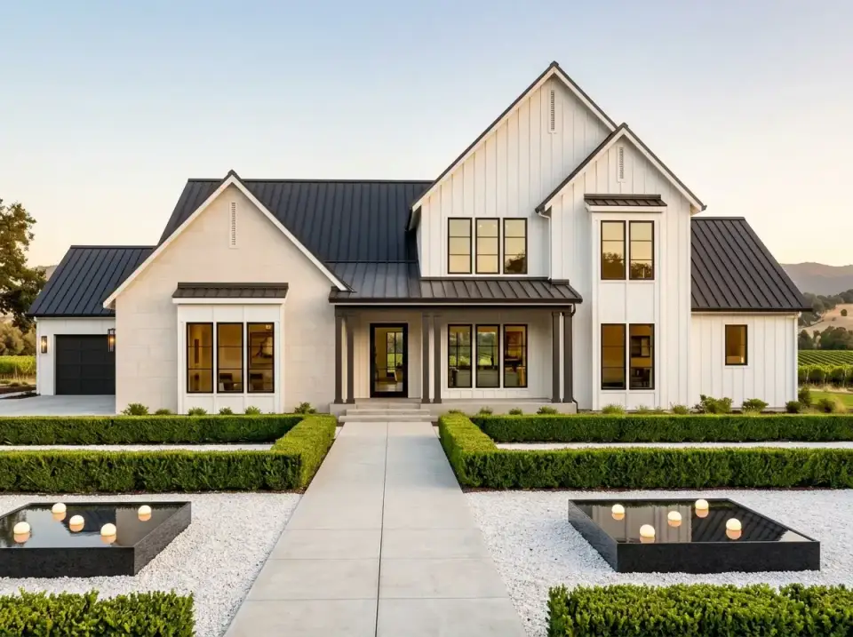 Contemporary white farmhouse facade with dark metal roof and minimalist landscaping