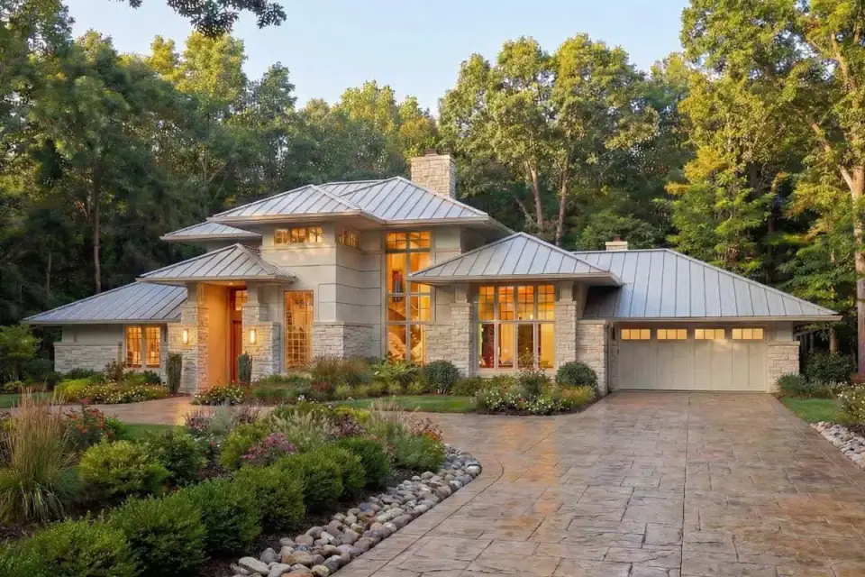 Contemporary 2-story exterior with Prairie-influenced low-pitched hip roof, mixed stucco and stone veneer, and metal roofing