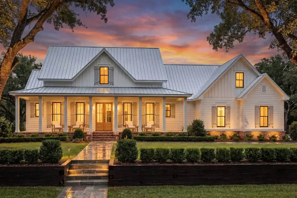 Front elevation of the modern farmhouse showing wrap-around porch board-and-batten siding stone veneer accents and standing-seam metal roof