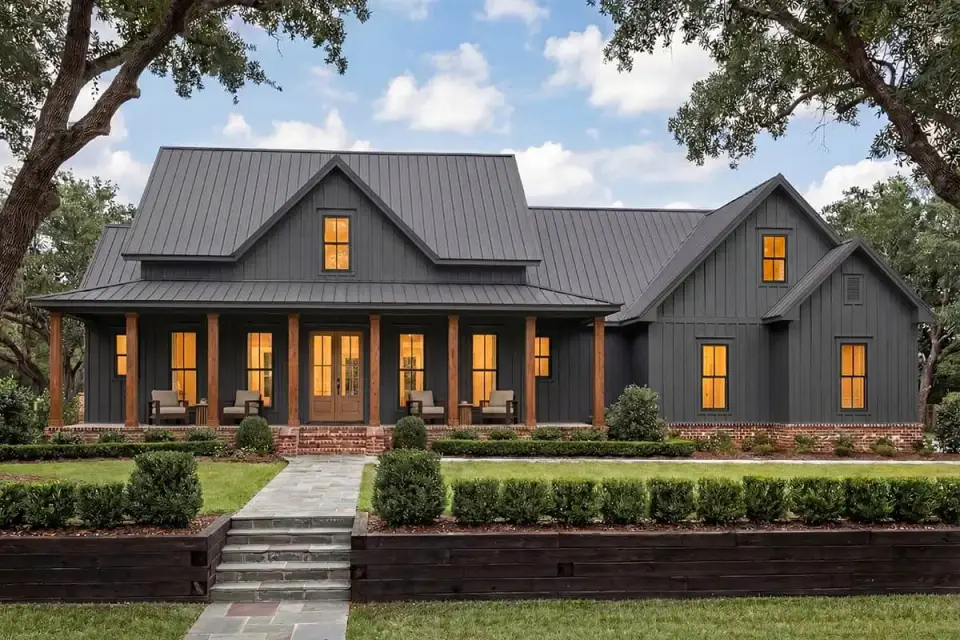 Three-quarter view highlighting the prominent gable dormers tall shuttered windows and cedar porch columns