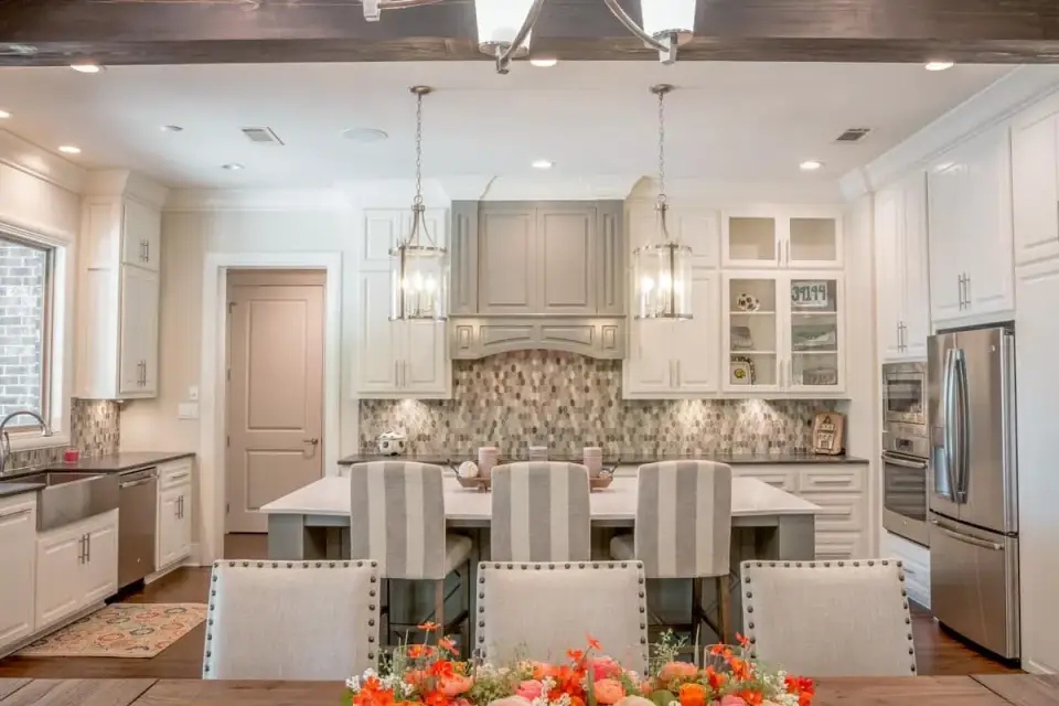 Great room interior of Plan 51814HZ featuring a brick-surround fireplace, exposed Douglas fir timber beams on the vaulted ceiling, an open connection to the dining and kitchen, and wide-plank white oak flooring