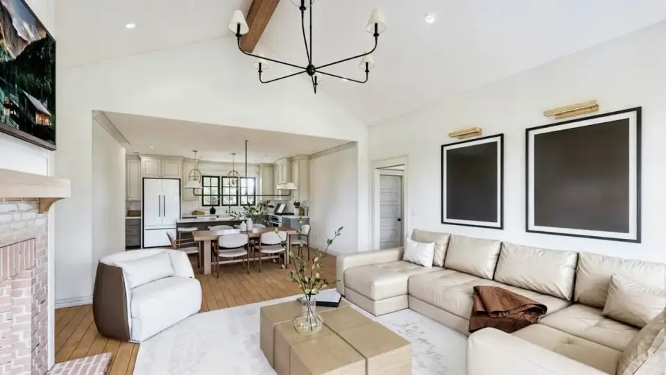 Vaulted great room interior with exposed beams, stone fireplace, and hardwood flooring