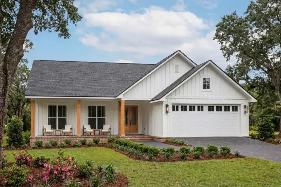 Three-quarter view of the modern farmhouse showing the front porch returning along the side and the side-entry garage approach