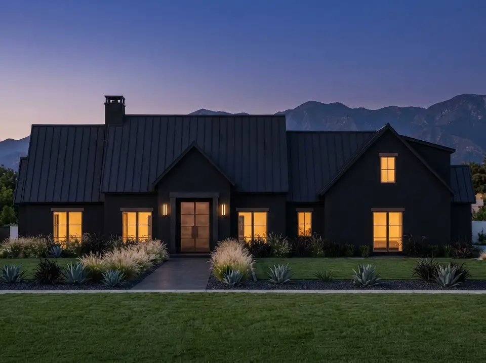Black and bronze facade of plan 818204JSS at dusk with matte black stucco, black metal roof, bronze front door and warm lit windows