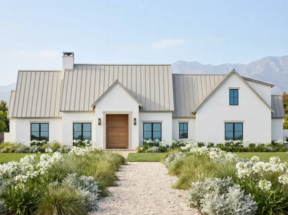 Coastal white and teak facade of plan 818204JSS with bright white stucco, pale pewter metal roof, teak front door and white agapanthus