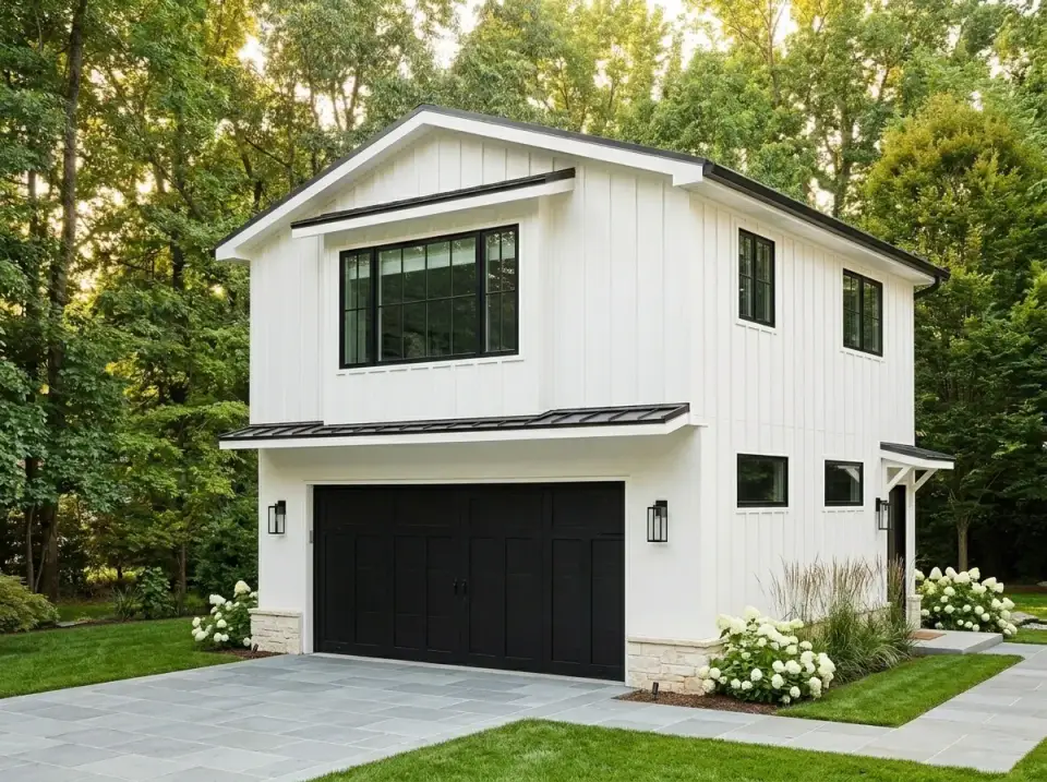 Modern farmhouse ADU facade with vertical white board-and-batten, matte black garage door, and stone wainscoting at the corners