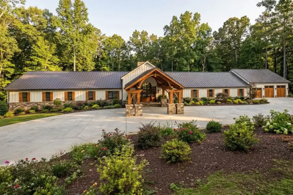Barndominium exterior with dark standing-seam metal roof, stone wainscot, and heavy timber entry portico
