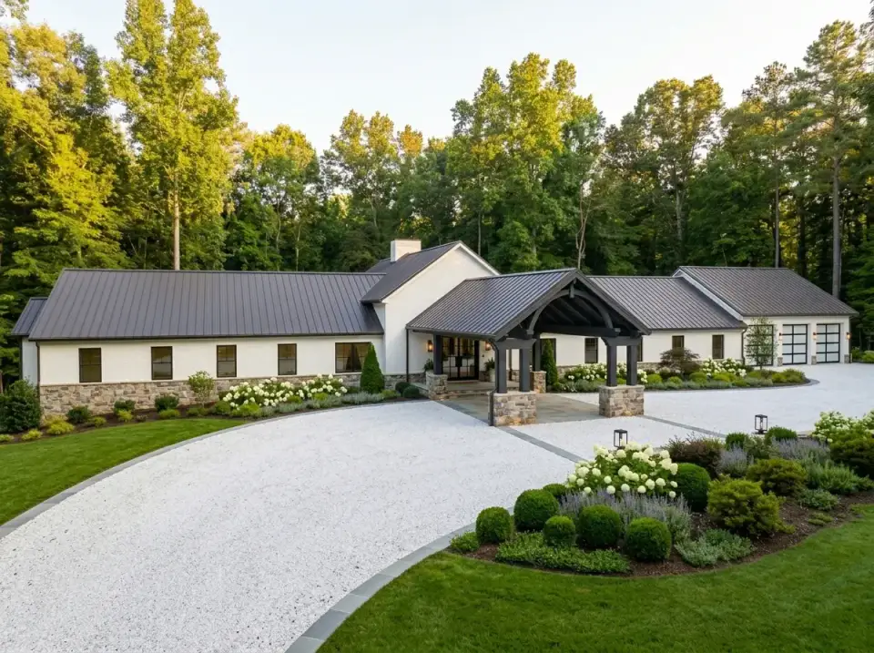 Traditional country estate barndominium with light walls, dark metal roof, boxwood spheres, and lavender borders