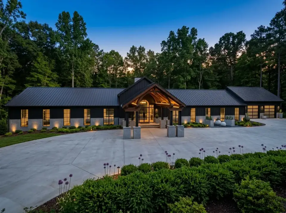 Twilight modern lodge barndominium with darkened cladding, illuminated portico, and integrated exterior lighting