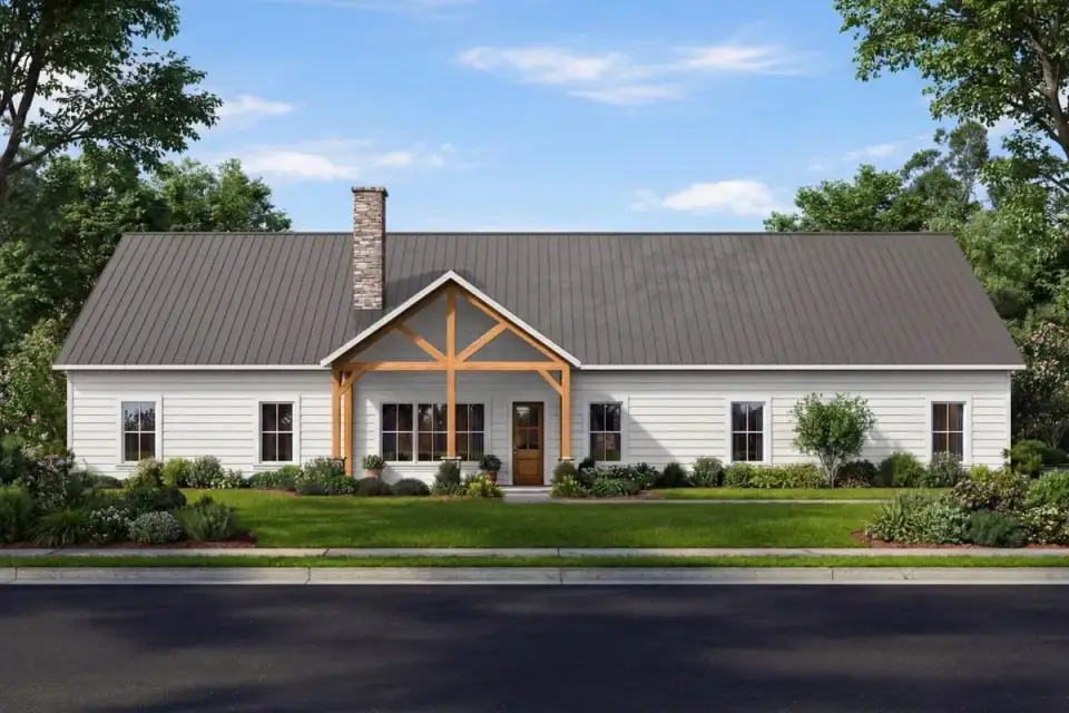 Country barndominium front elevation with broad gabled standing-seam metal roof, exposed timber trusses over centered entry porch and stone chimney