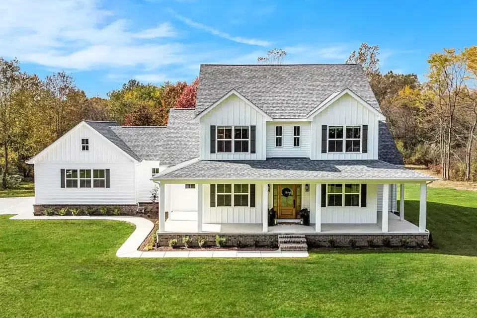 Front elevation of the country farmhouse showing gabled roof, dormer windows, and wrap-around covered porch