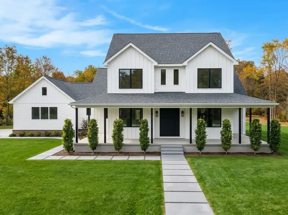 Crisp white modern farmhouse with black window frames, black porch posts, and structured paver walkway